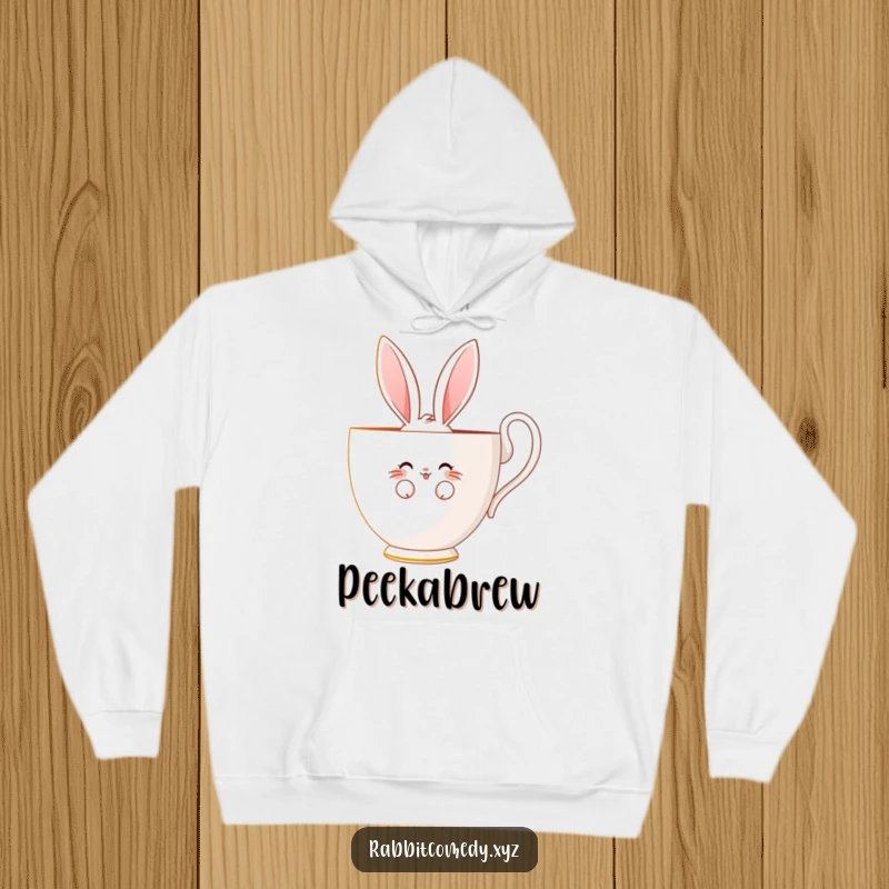 Funny hoodie with a shy rabbit character peeking bashfully from behind a giant teacup, offering a cute, endearing smile.