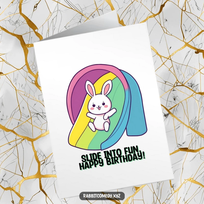 Funny free printable birthday card showing a kawaii rabbit gleefully sliding down a vibrant rainbow slide.